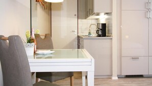A modern kitchen with white cabinets, a glass dining table, and a hanging pendant light. - Ferienwohnungen Grosser und Kleiner Seestern, Wiek (Wiek)