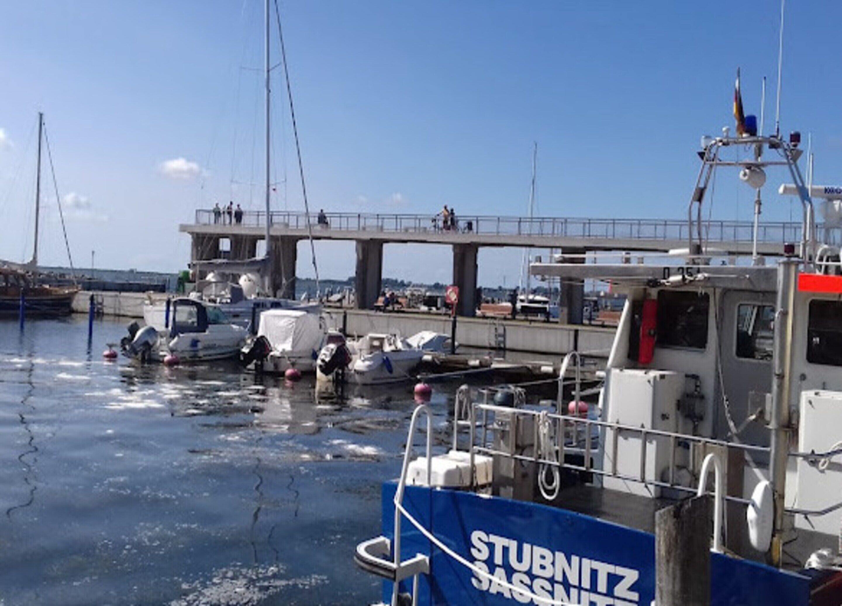 Un puerto deportivo con barcos amarrados, un puente y una embarcación llamada 'STUBNITZ SASSNITZ'.