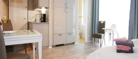 A compact hotel room with a kitchenette, a dining area, and a bed.