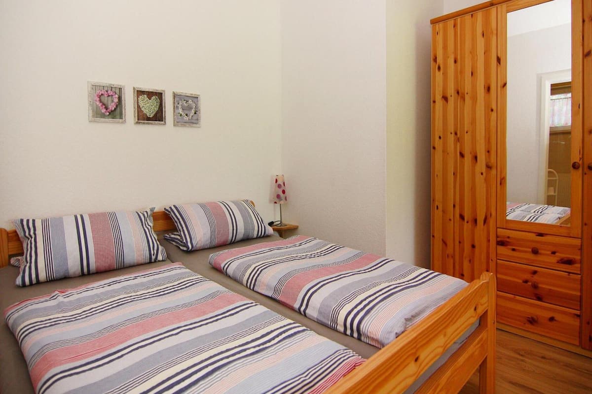 A bedroom with two single beds, a wooden wardrobe, and three heart-shaped wall decorations.