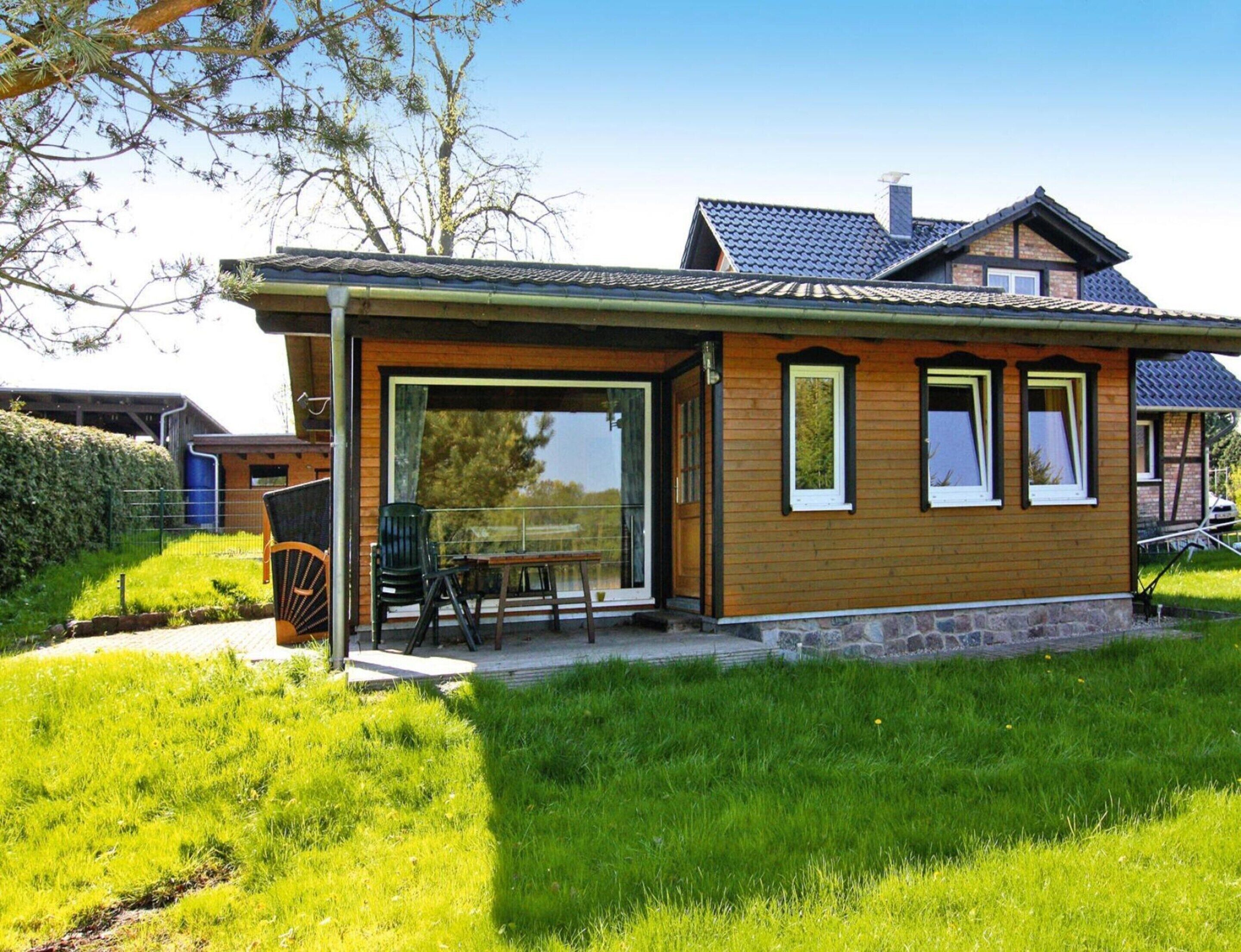A modern house with a wooden exterior, a patio with outdoor furniture, and a large glass door leading to a covered area.