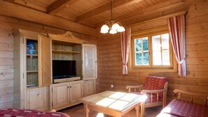 A cozy cabin interior with wooden walls, a television, a table, and two chairs. - Holiday Home in Stefan in the Lavanttal With Balcony (Frantschach-Sankt Gertraud)