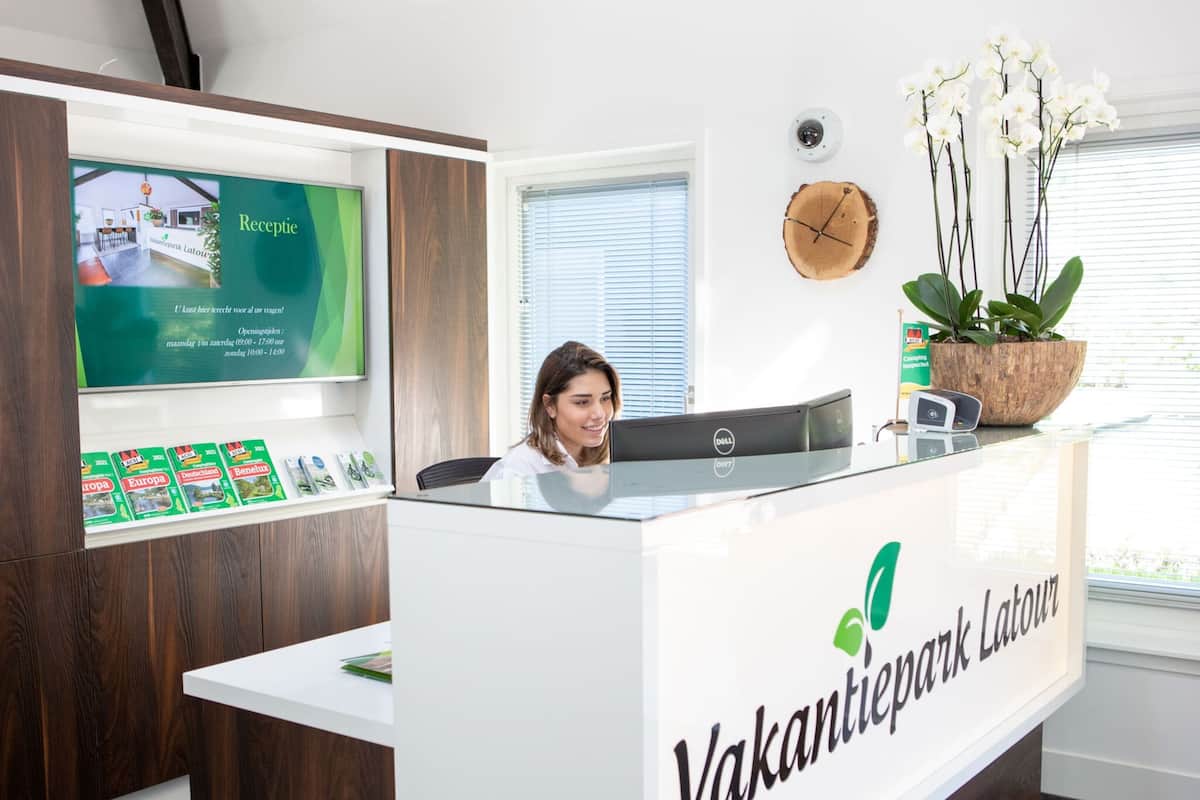 Un comptoir d’accueil avec une pancarte indiquant « Vakantiepark Latour ».