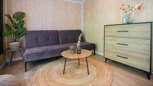 Una sala moderna con un sofá gris, un mueble de madera, una mesa de centro redonda y una planta en maceta.