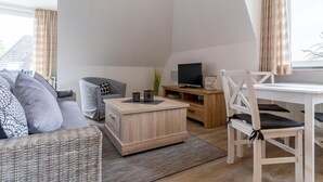A modern living room with a sofa, a coffee table, a TV, and a dining area. - Apartment, Tating (Tating)