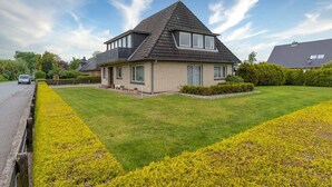 A two-story house with a sloped roof, a front lawn, and a driveway. - Apartment, Tating (Tating)