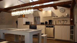 A modern kitchen with wooden beams, a chandelier, a refrigerator, a microwave, a coffee maker, and a dishwasher.