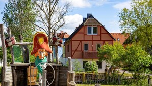 Een houten constructie in rustieke stijl met een persoon, een huis en een omheind gebied.