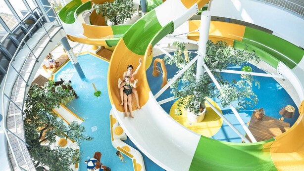 Een meerlaags overdekt waterpark met glijbanen en zwembaden.