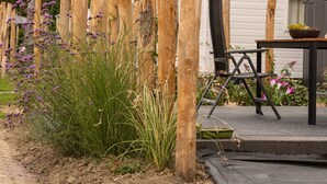 A wooden fence, a table with chairs, and a building in the background. - Comfortable Chalet With Airco, on a Holiday Park, at Just 1 km. From the Beach (Koudekerke)