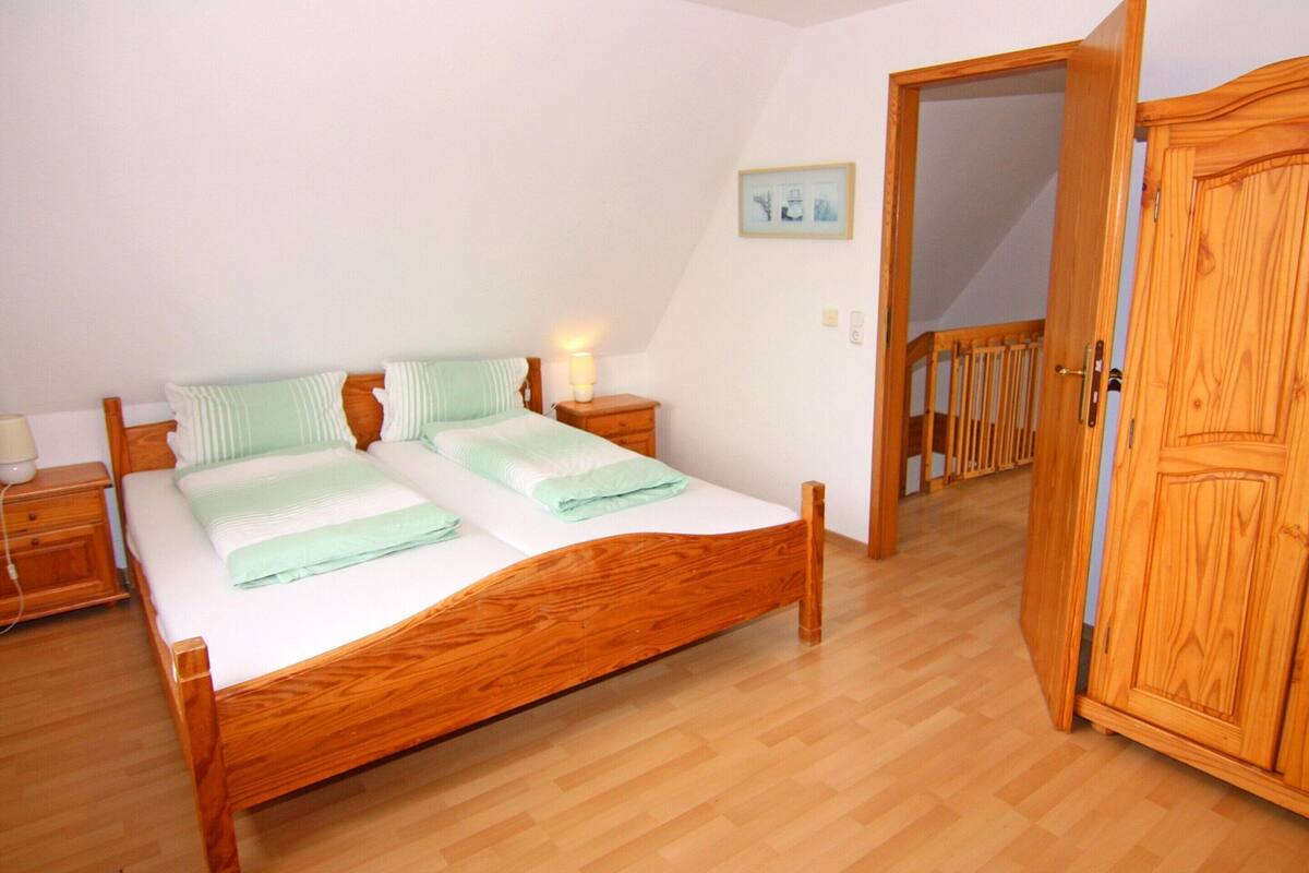A bedroom with a wooden bed, a nightstand, a bedside table, and a wooden wardrobe.