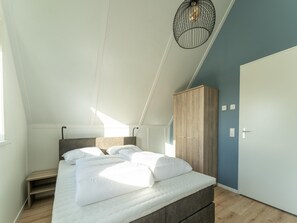 A bedroom with a bed, wooden wardrobe, and a hanging light fixture. - Beautiful Holiday Home in Scherpenisse With Charming Terrace (Scherpenisse)