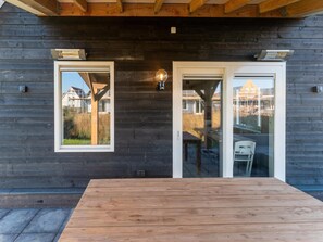 A wooden exterior with a glass door and windows, a wooden table, and a light fixture. - Beautiful Holiday Home in Scherpenisse With Charming Terrace (Scherpenisse)