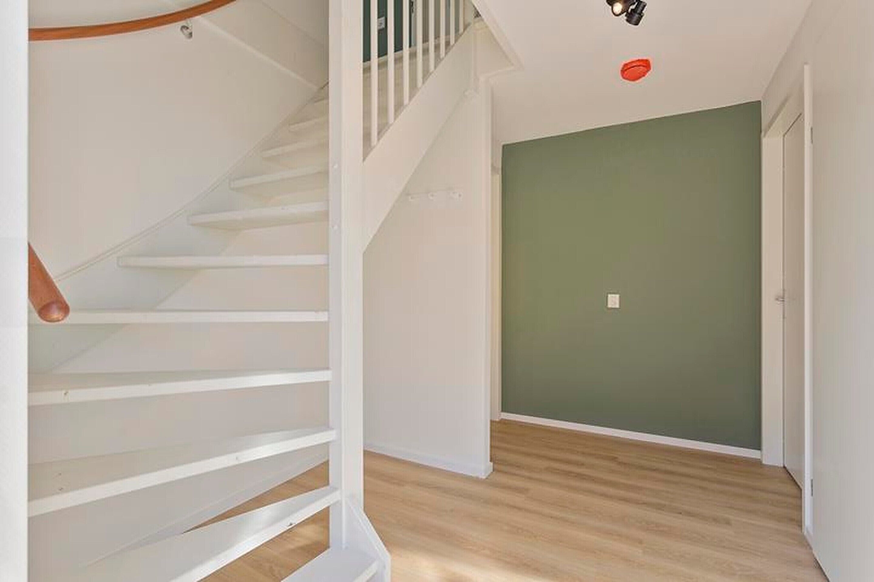 A staircase with white railings and a wooden handrail leading to a landing.