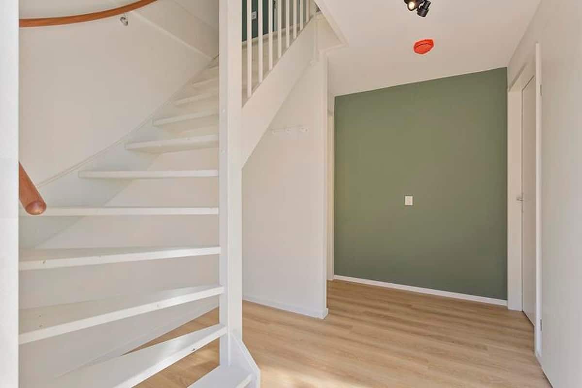 A staircase with white railings and a wooden handrail leading to a landing.