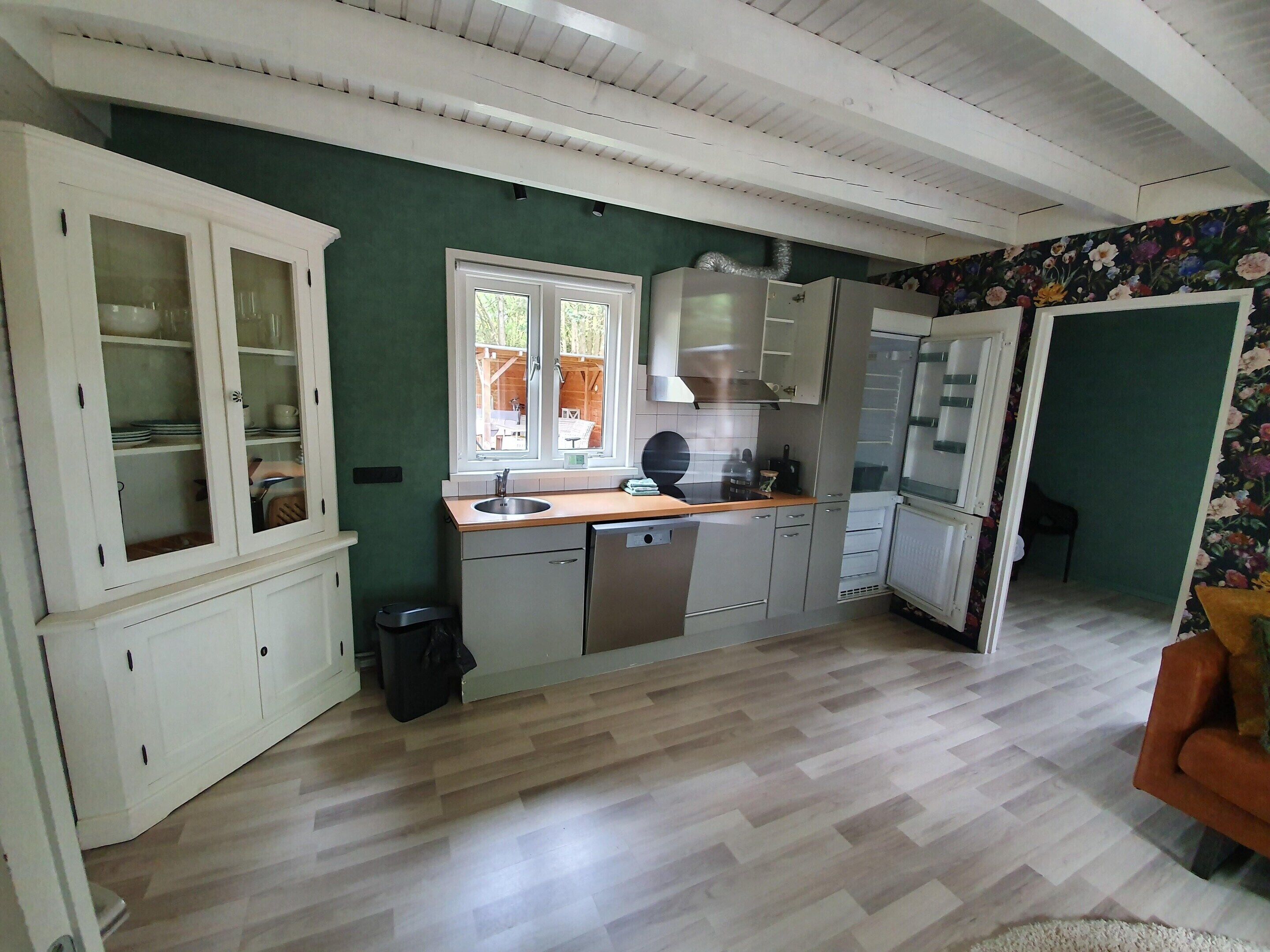 A kitchen with a window, wooden cabinets, a sink, and a refrigerator.