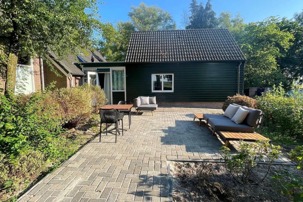 Un espace extérieur aménagé avec une table et des chaises, un canapé et un petit jardin.