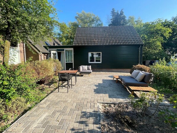 Un patio con mesa y sillas, un sofá y un pequeño jardín.