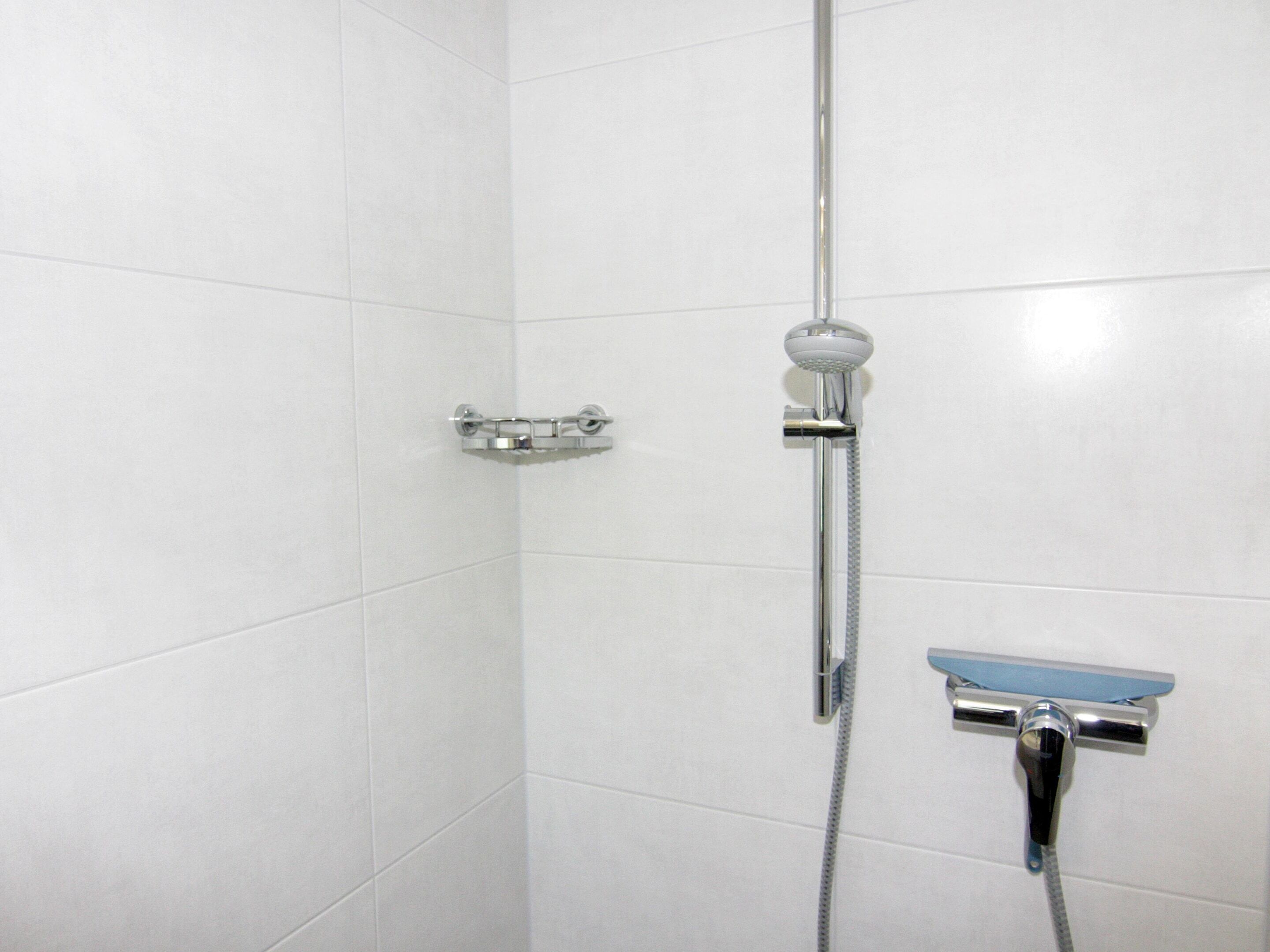 A shower with a handheld showerhead, a handheld shower attachment, and a handheld faucet.