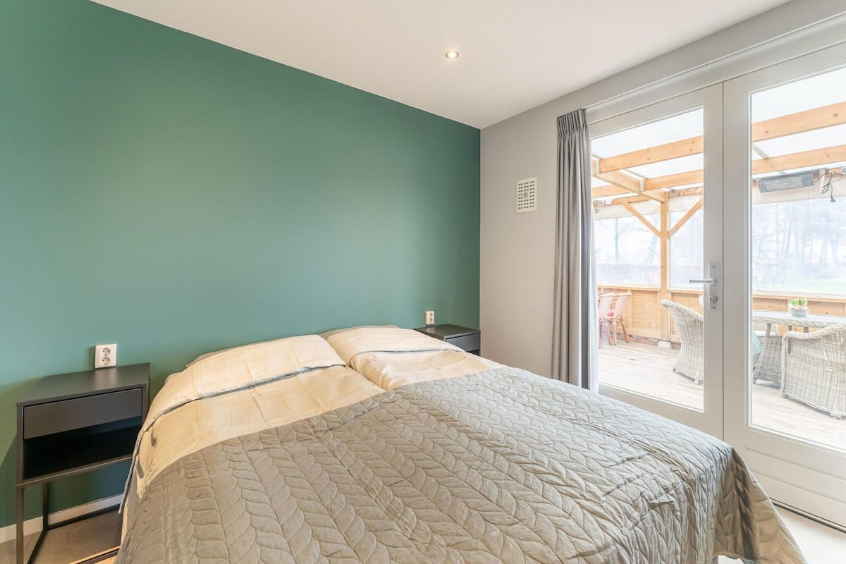 Une chambre à coucher avec un lit, une table de chevet et une vue sur une terrasse extérieure.