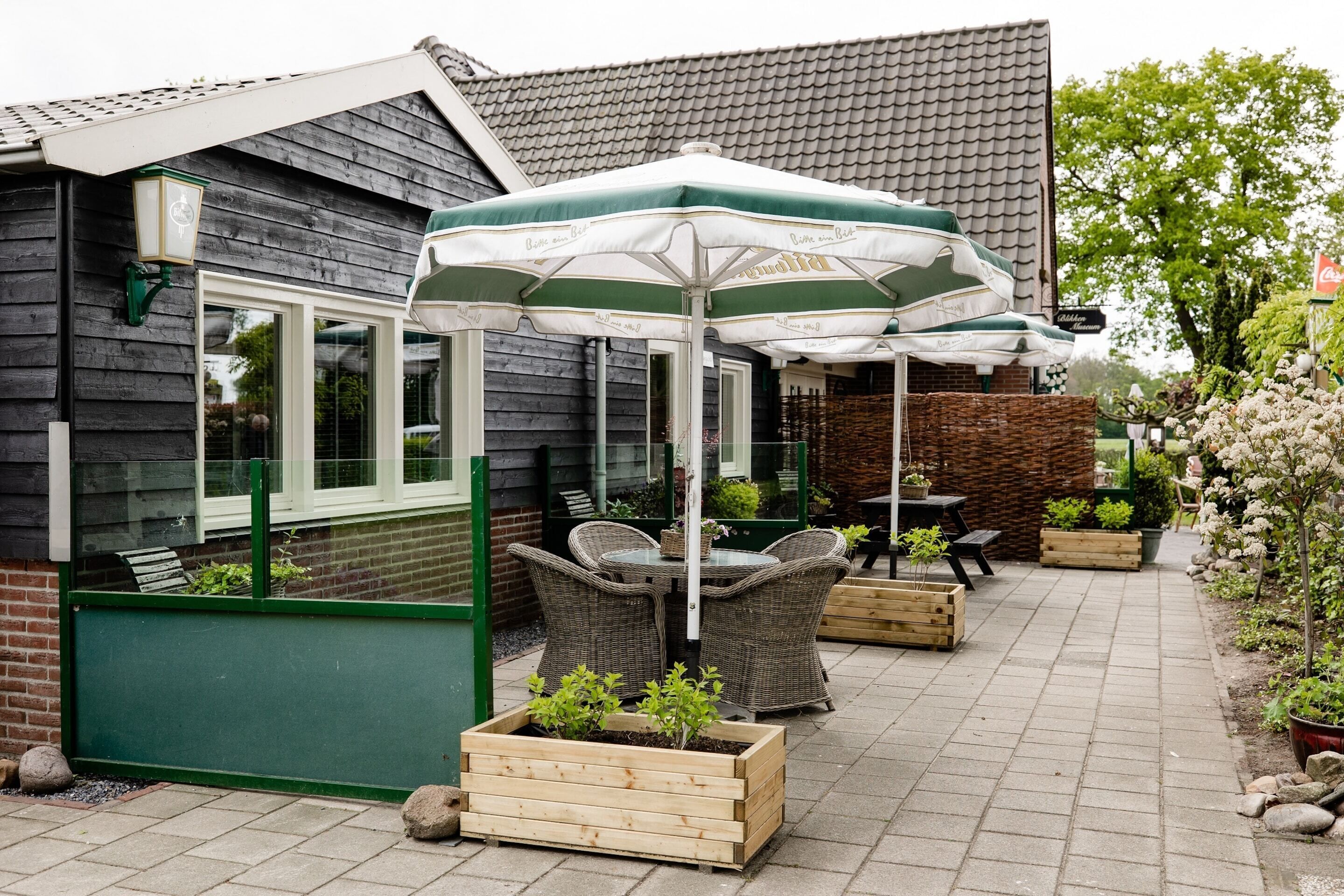 A patio area with wicker furniture, a table, and a green and white umbrella.
