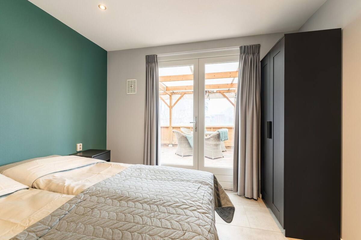 Une chambre avec deux lits, une porte-fenêtre coulissante donnant sur un balcon et une armoire sombre.