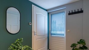 A hallway with a white door, a window with blinds, and two potted plants. - Charming House With Garden in Rural Area Hellendoorn (Hellendoorn)