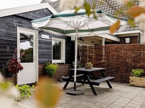 A patio with a table and umbrella, surrounded by plants and a brick wall.