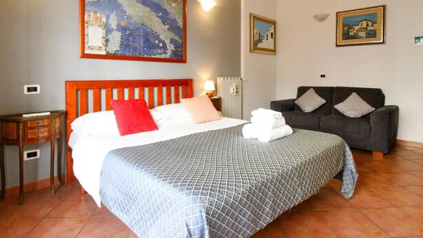 A hotel room with a bed, a sofa, a painting, and a radiator. - Holiday Flat in Central Location in Rome (Rome)