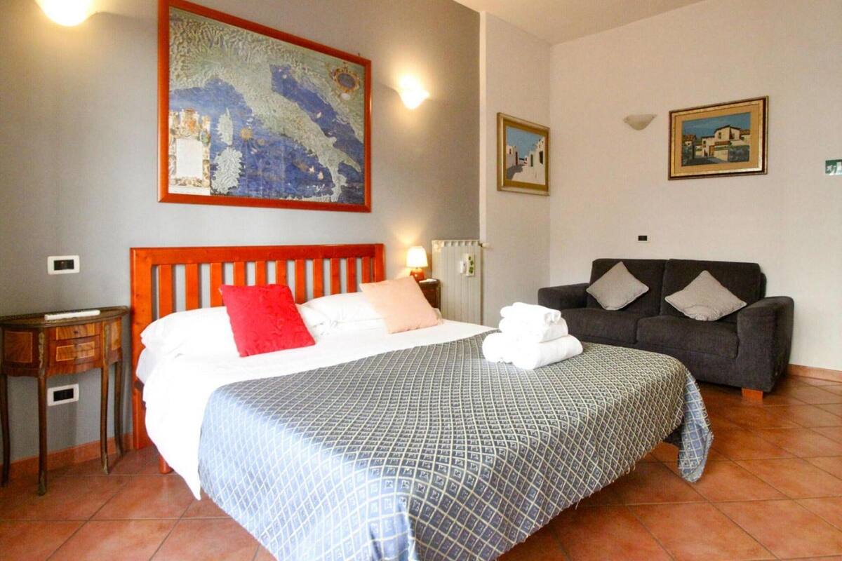 Una habitación de hotel con una cama, un sofá, un cuadro y un radiador.