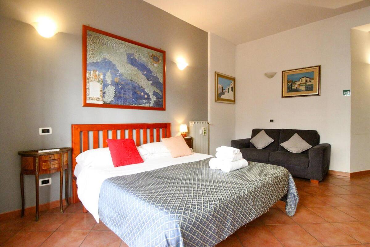 Una habitación de hotel con una cama, un sofá, una mesita de noche y obras de arte en las paredes.