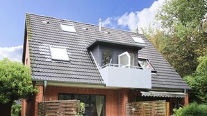 A two-story house with a sloped roof, a small balcony, and a brick exterior. - Apartment, St. Peter-ording (St. Peter-Ording)