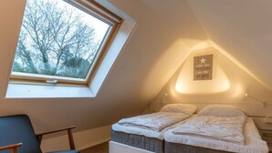 A bedroom with a skylight, a bed with two pillows, a bedside table, and a chair. - Apartment, St. Peter-ording (St. Peter-Ording)