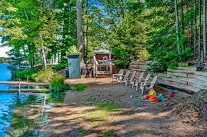 A lakeside cabin with a dock, outdoor seating, and a small deck area. - Pine & Paddle PLUS (Saint Germain)