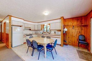 A compact kitchen with a central island, white cabinets, and a microwave. - Pine & Paddle PLUS (Saint Germain)