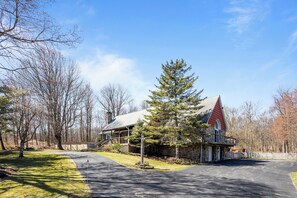 A two-story house with a red roof, a stone foundation, and a front porch.
