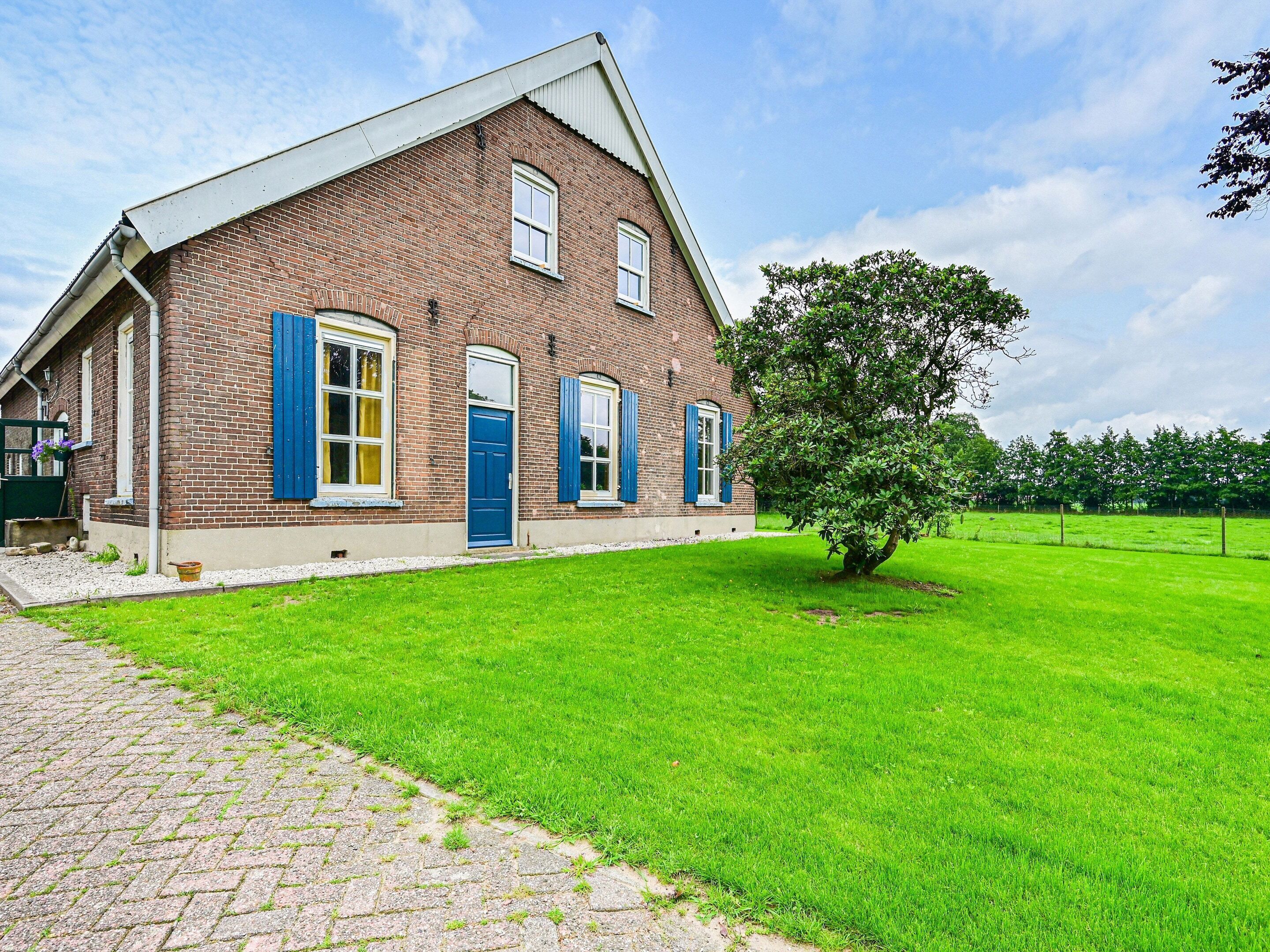 Une maison en briques avec des volets bleus, une allée pavée et une pelouse bien entretenue.