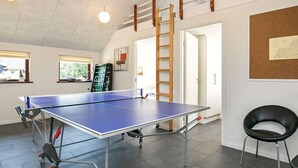Ett bordtennisbord i ett rum med högt i tak, en stege och en karta på väggen.