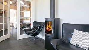Ett modernt vardagsrum med en svart lädersoffa, en svart läderfåtölj och en svart vedkamin.