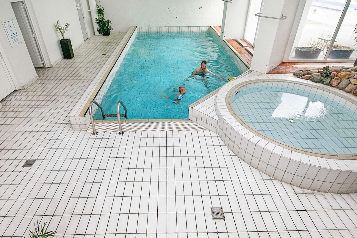 An indoor swimming pool with tiled floors and a separate hot tub area.