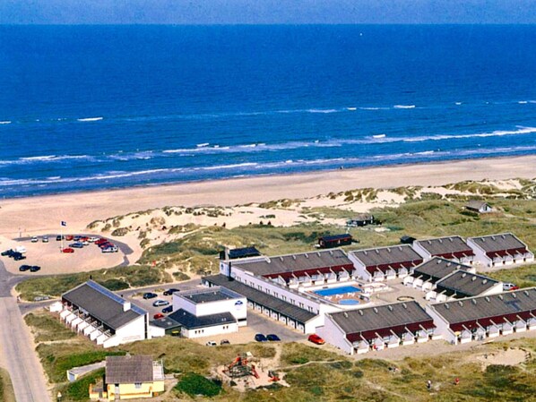 Un hôtel situé sur la côte, doté de nombreuses chambres, d’une piscine et offrant une vue sur la plage.