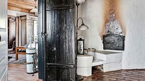 A rustic room with a wooden door, a white bench, a lantern, and a fireplace. - 4 Person Holiday Home in Kivik (Kivik)