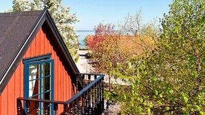 A red building with a blue window and balcony railing, surrounded by trees and a clear sky. - 4 Person Holiday Home in Kivik (Kivik)