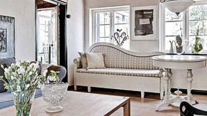 A cozy living room with a wooden table, a sofa, and a white wall with a decorative mirror. - 4 Person Holiday Home in Kivik (Kivik)