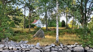 A house surrounded by trees and a stone wall by a body of water. - 4 Person Holiday Home in Kyrkhult (Kyrkhult)