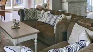 A living room with a brown sofa set, a white coffee table, and a cabinet with glass doors. - 4 Person Holiday Home in Kyrkhult (Kyrkhult)