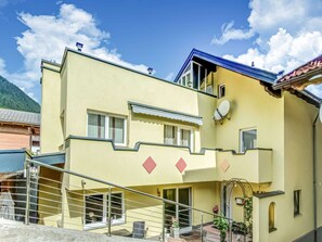 A two-story building with a balcony, a satellite dish, and a staircase leading to the entrance. - Nice Apartment in Sautens With a Cozy Terrace (Sautens)