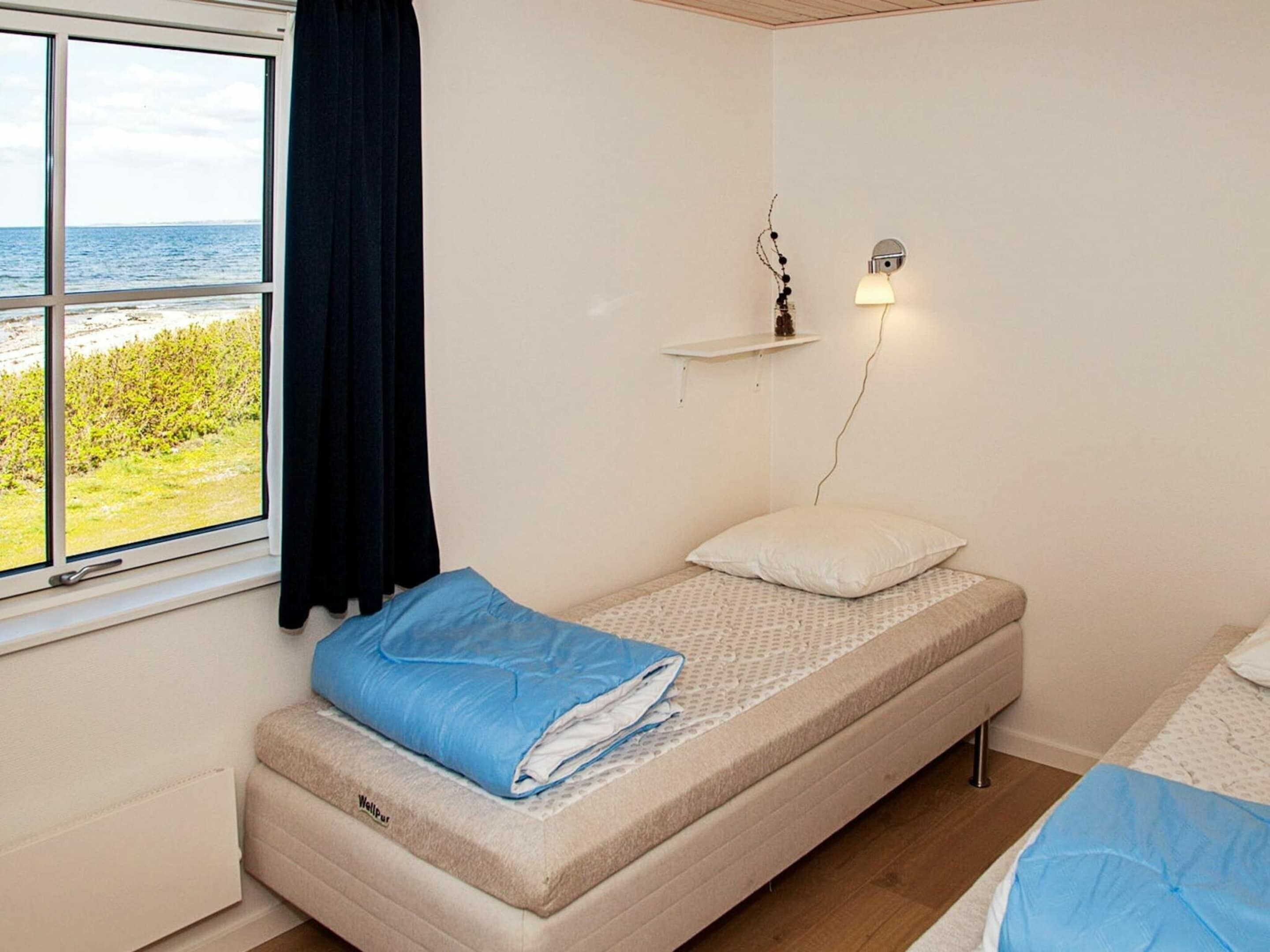 A small, single-bed room with a view of the sea through a window.