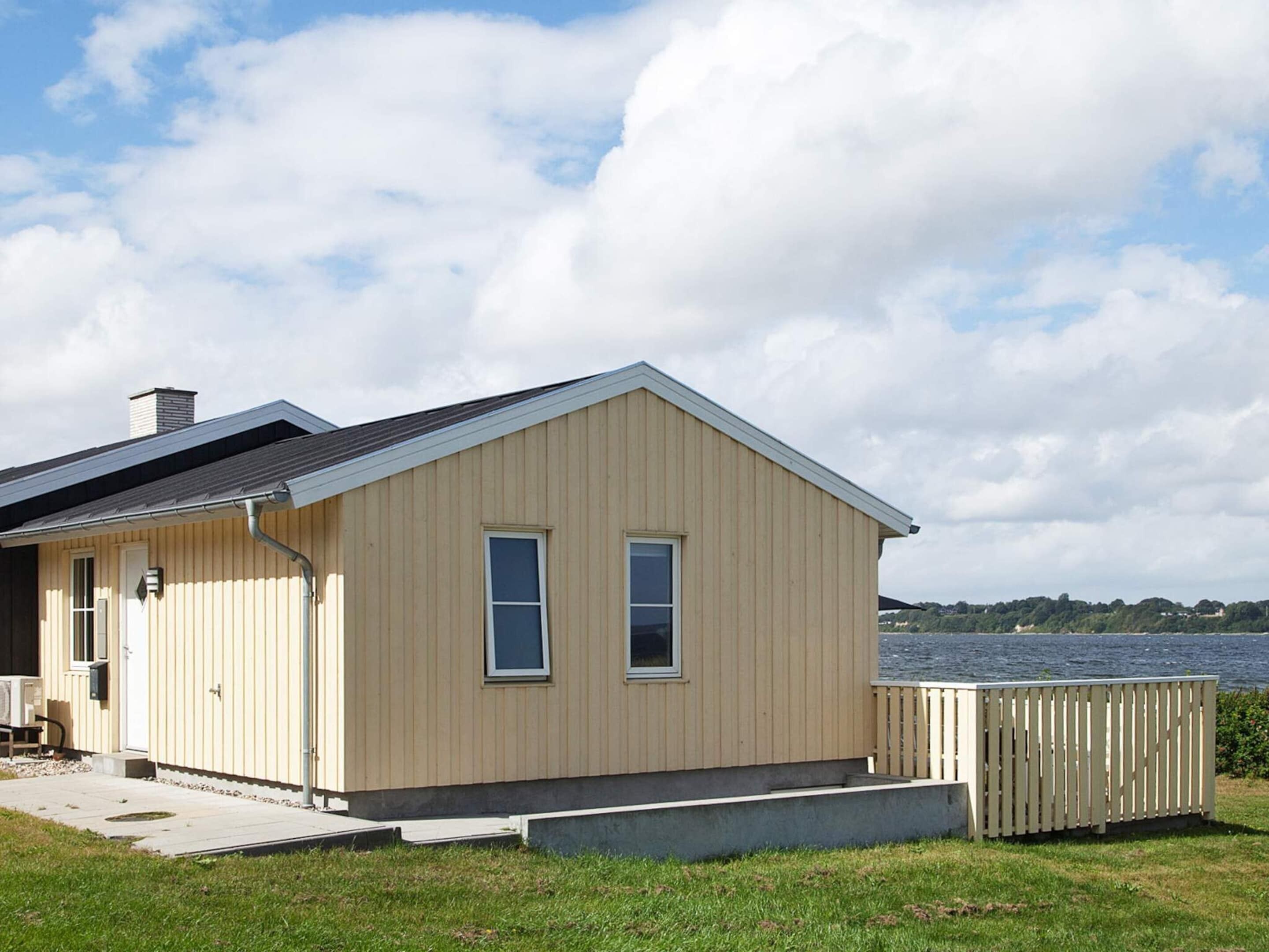 A single-story building with a gabled roof, a small porch, and a view of a body of water.