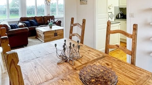 Uma área de jantar com mesa de madeira, cadeiras, uma taça de vidro decorativa e um candelabro.